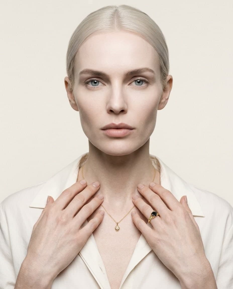 La bague à la main d’un mannequin, à hauteur de la clavicule, sur fond ivoire